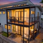 Modern white townhouse complex with multiple garages and a paved driveway under a clear blue sky.