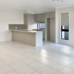 Empty open-plan kitchen with gray cabinets, a central island, and tiled floor.
