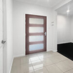 Wooden door with four frosted glass panels in a bright hallway.