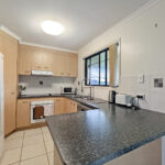 Bright kitchen with beige cabinets, white fridge, and a dark speckled island countertop.